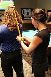 Amber Eberhard, a waitress at Fox and Hound, measure's Steve's hair. Photo by Bethany Turner