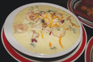 Oasis' shrimp and grits, featuring sauteed shrimp, onions, peppers, and bacon in a heavy cream served over cheese grits.