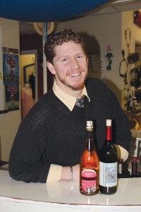 Beau Walker is an employee of Silver Coast Winery Tasting Room and a contributor to Southport Magazine. On the left is a bottle of McKeown's Cranberry Cider, while Silver Coast Winery's own Holiday Red appears on the right. Photo by Bethany Turner