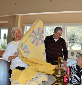 Judy Bowers displays her antique quilt, while Robert Brown (center) and Carol Mahoney (right) examine the piece. Brown and Mahoney are both appraisers from Northrop Antiques Mall in Southport. Courtesy photo