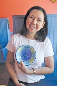 Thitima Sanitniam, better known as Gai, opened Thai by the Sea on Oak Island 11 years ago. The colorful bowl she holds is the only one left of a set that was inspiration for the upbeat color palette used in the restaurant. Photo by Bethany Turner