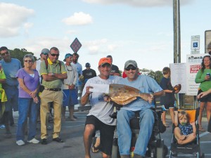 Fisherman Mike Hill (left) accepts the first place prize, $1,000 and  a 24-inch copper trophy, during the 2013 Bay Creek Classic. Hill is pictured with Brandon Matthews (right), a local Southport fishing legend whose medical bills are supported by proceeds of the Bay Creek Classic. Courtesy photo